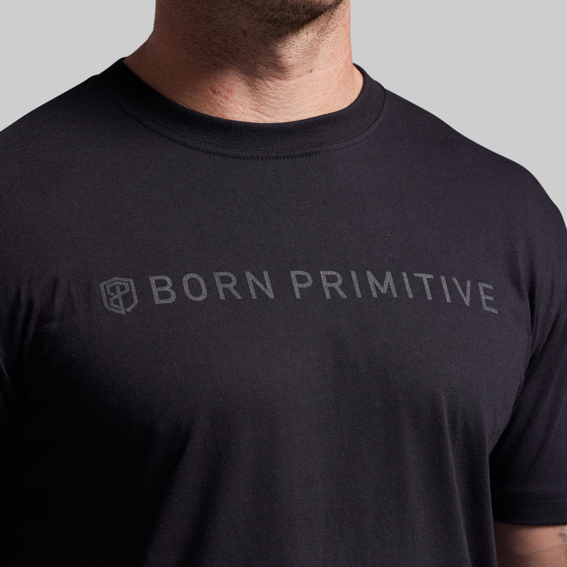 Black t-shirt with 'BORN PRIMITIVE' text on a gray background