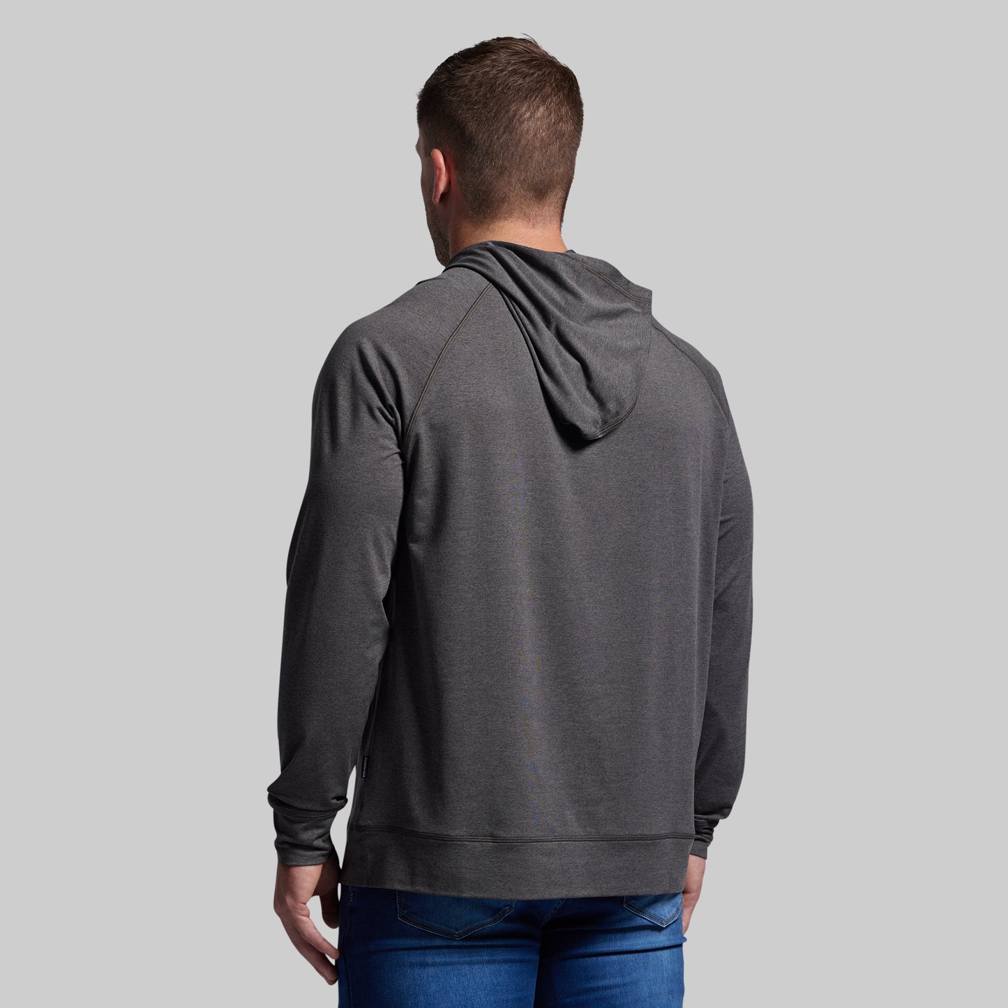 Person wearing a gray hoodie from behind on a light gray background