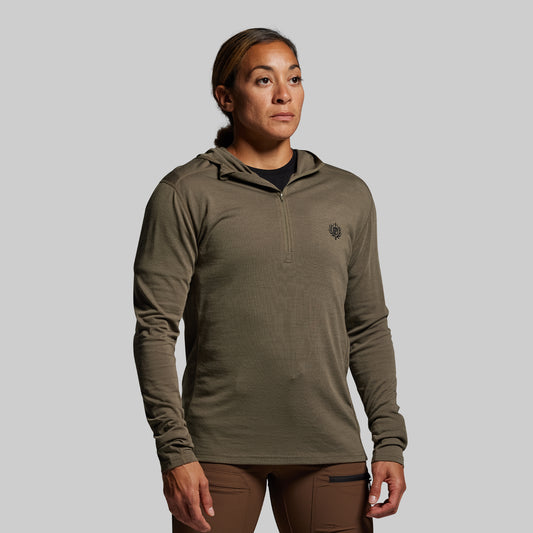 Person wearing a green long-sleeve shirt with a small logo on a gray background