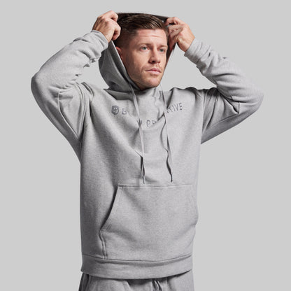 Man wearing a gray hoodie with branding on a light gray background
