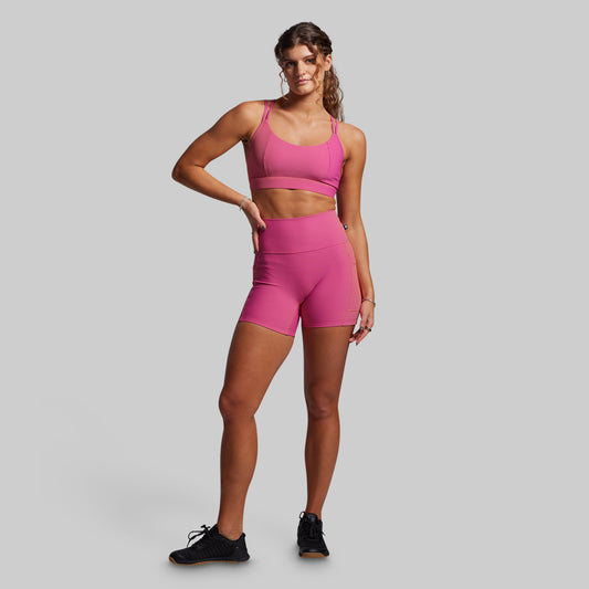 Women wearing pink ribbed athletic shorts on a gray background
