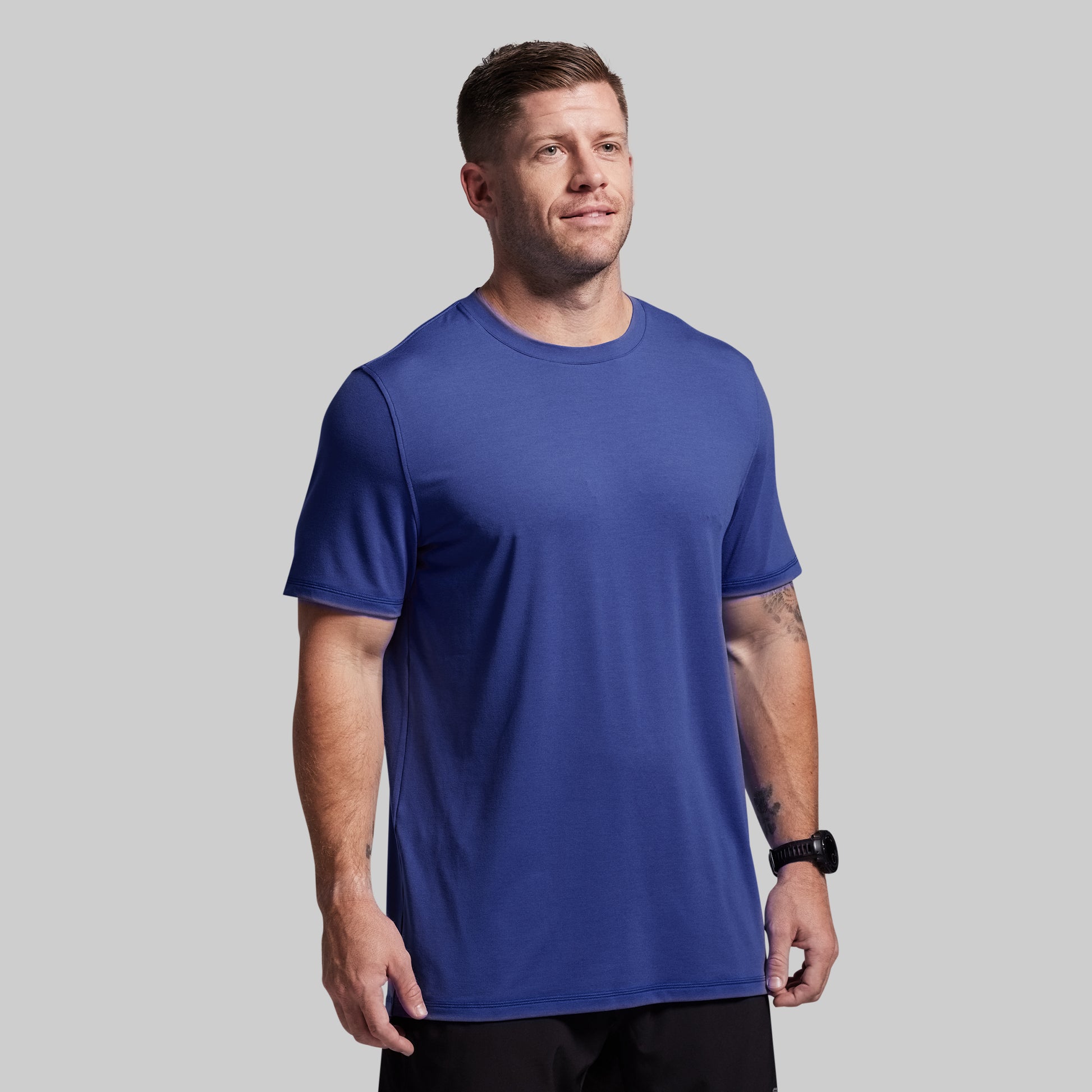 Man wearing a blue t-shirt against a gray background