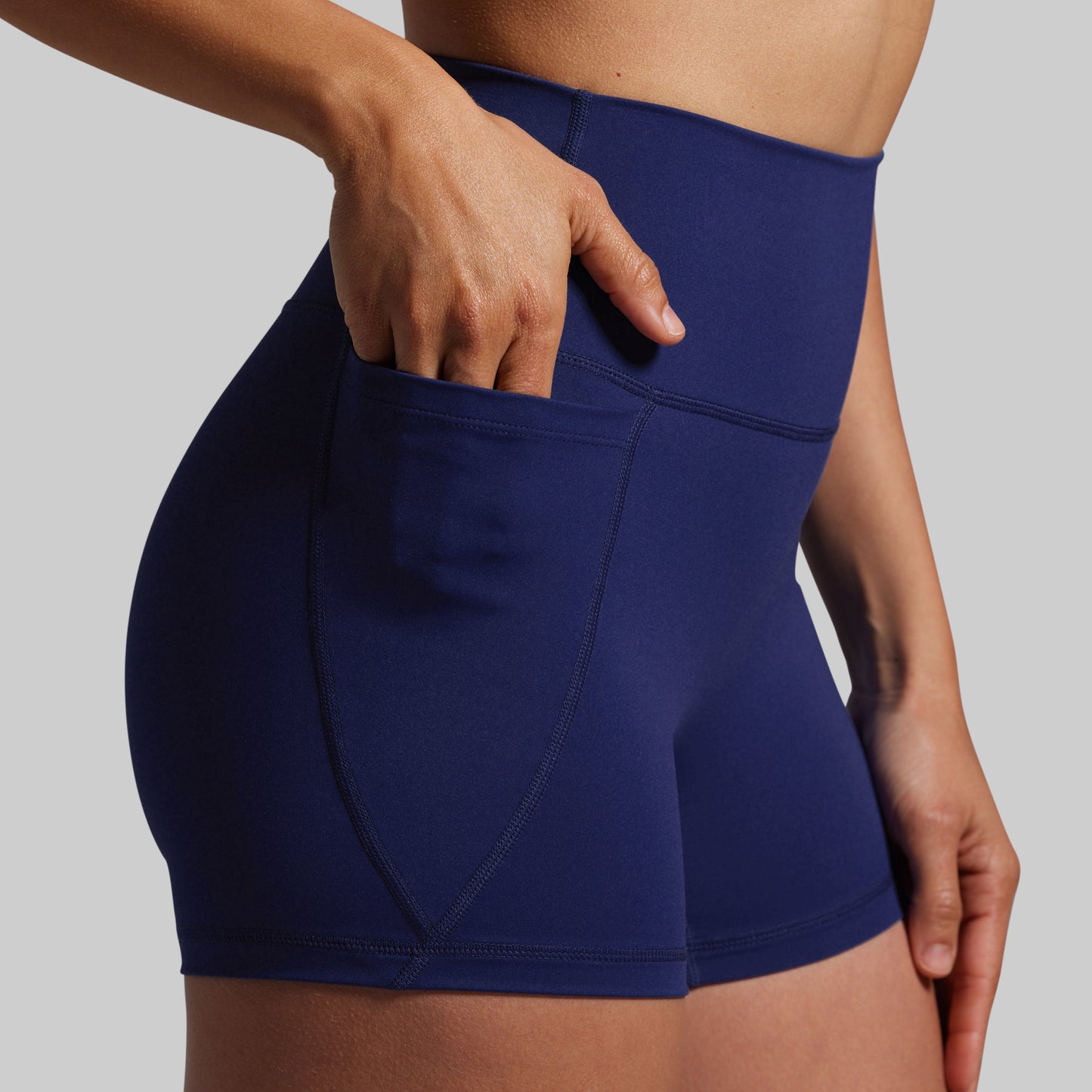 Navy blue athletic shorts with a pocket on a gray background
