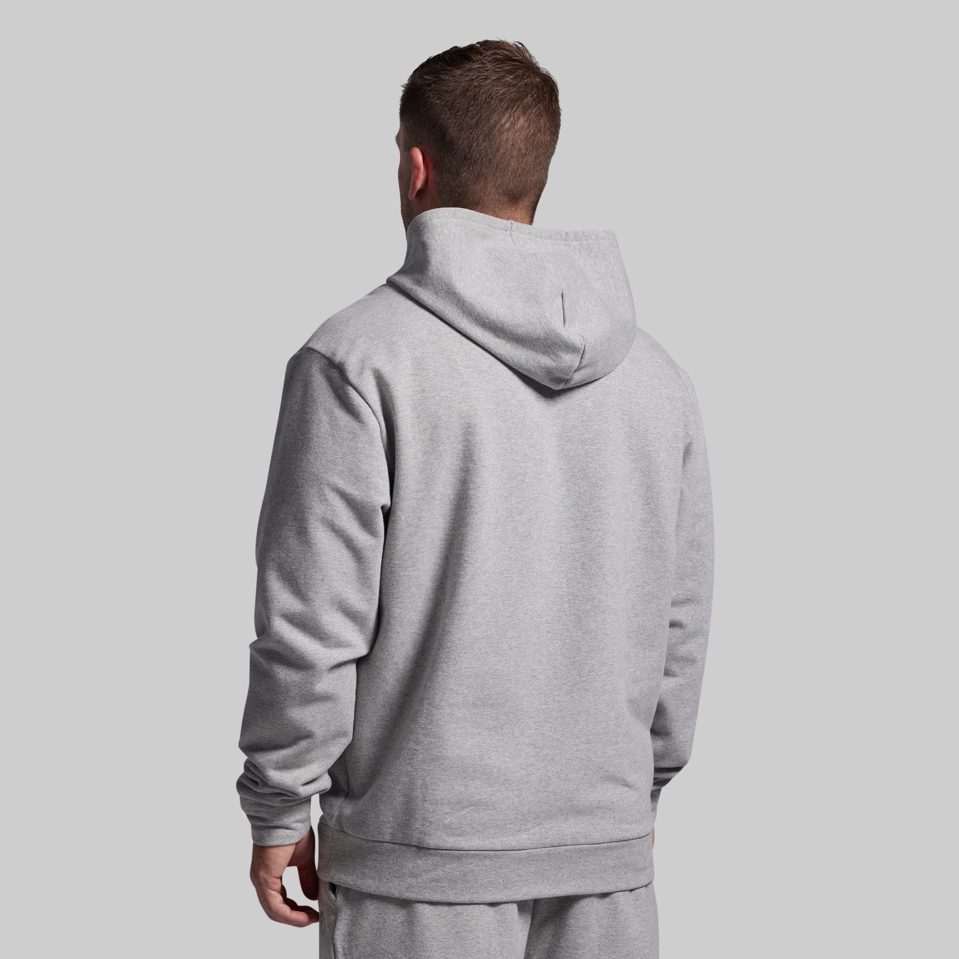 Person wearing a gray hoodie from behind on a light gray background