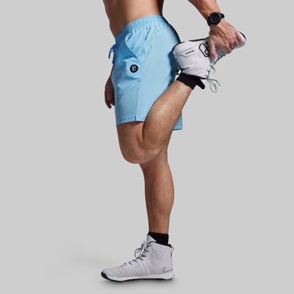 Person wearing light blue athletic shorts and white sneakers on a gray background