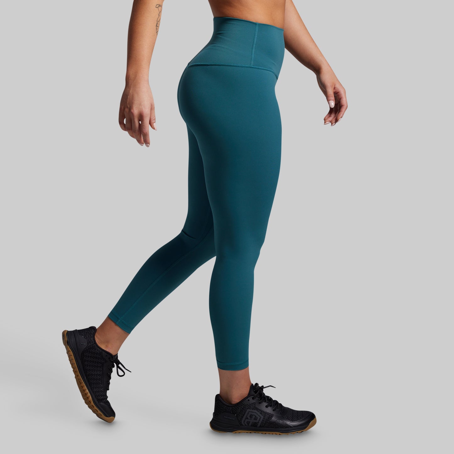Teal leggings worn by a person on a gray background