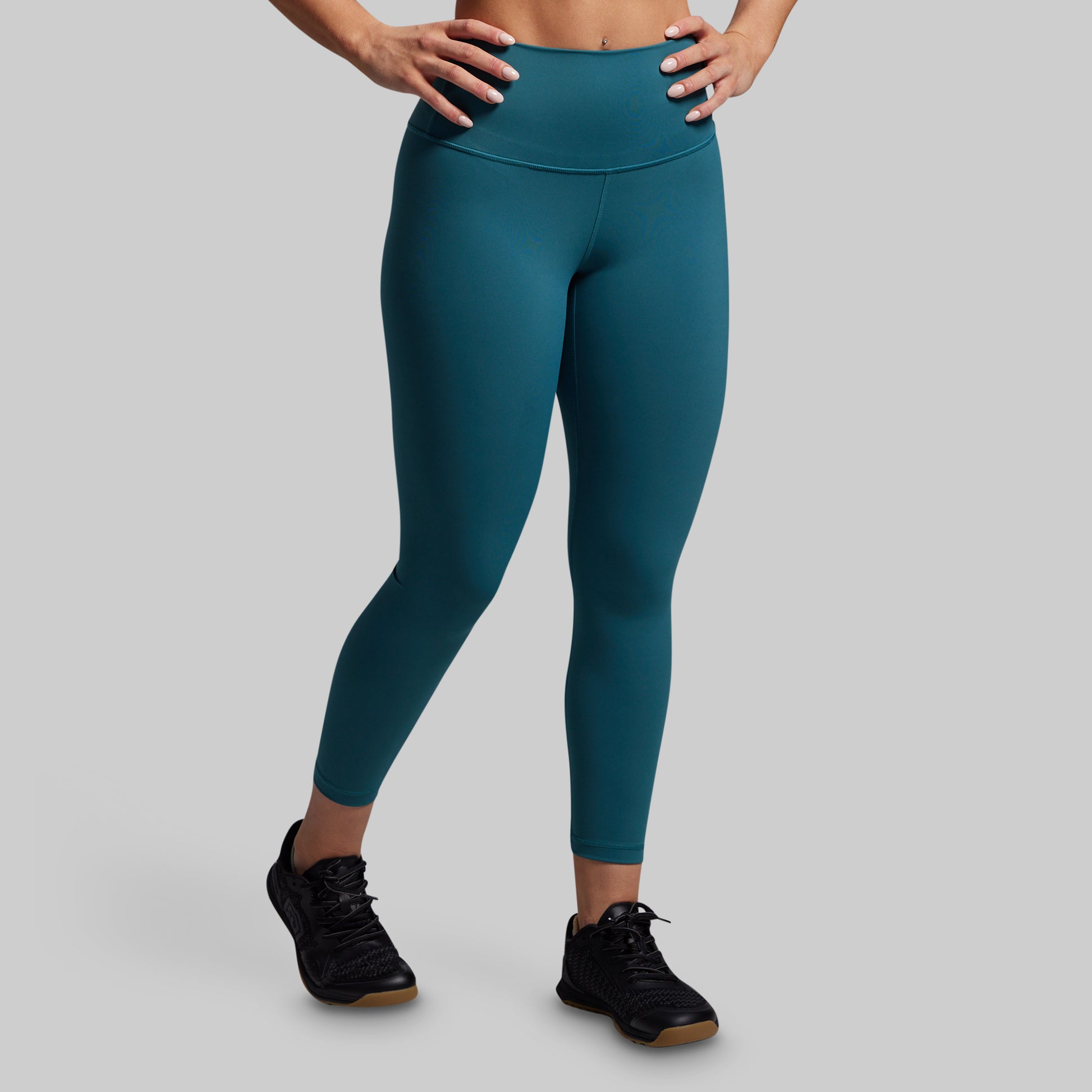 Teal leggings worn by a person on a gray background