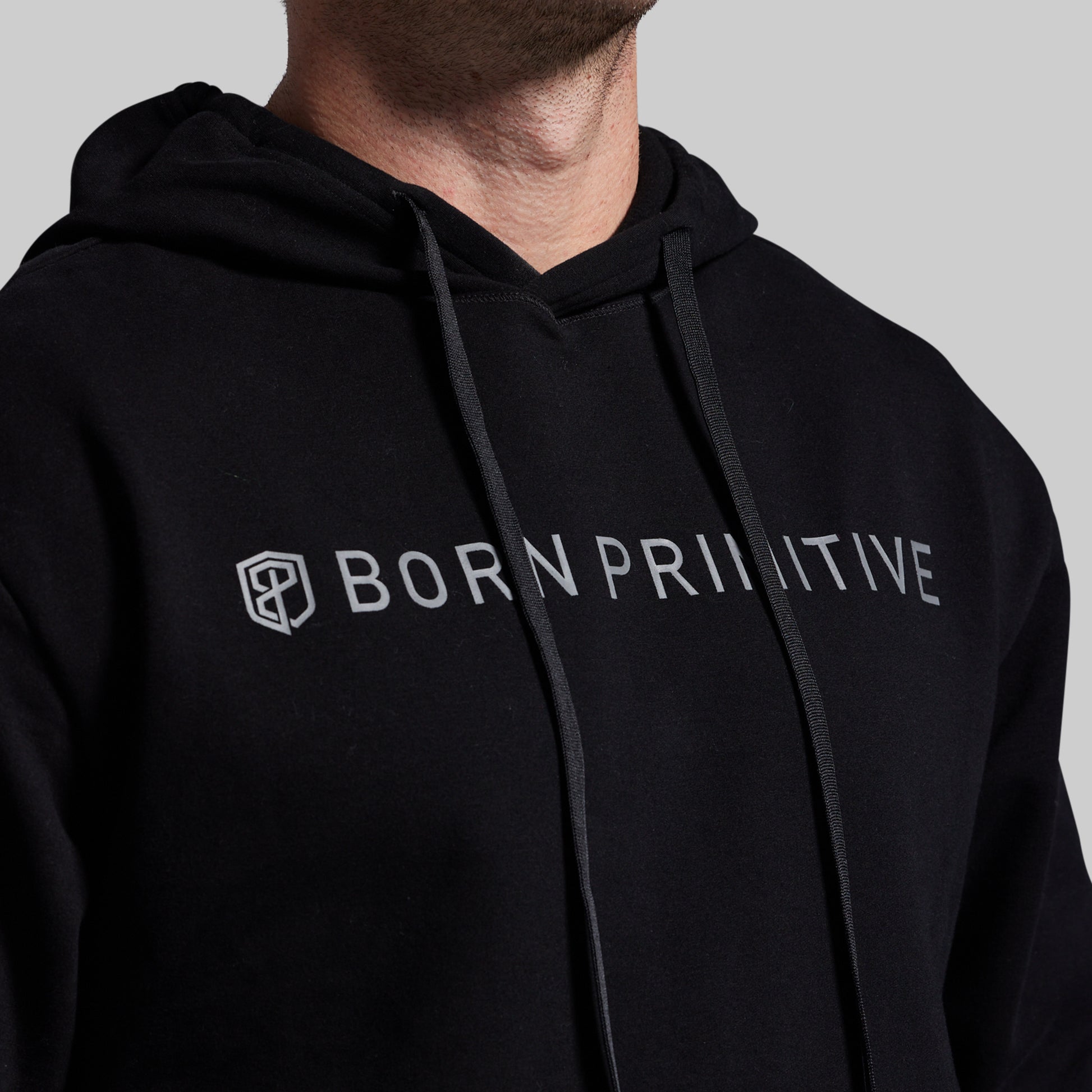 Black hoodie with 'Born Primitive' logo on a gray background