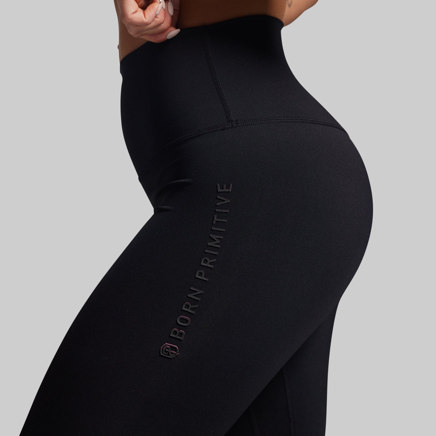 Black leggings with 'Born Primitive' branding on a gray background