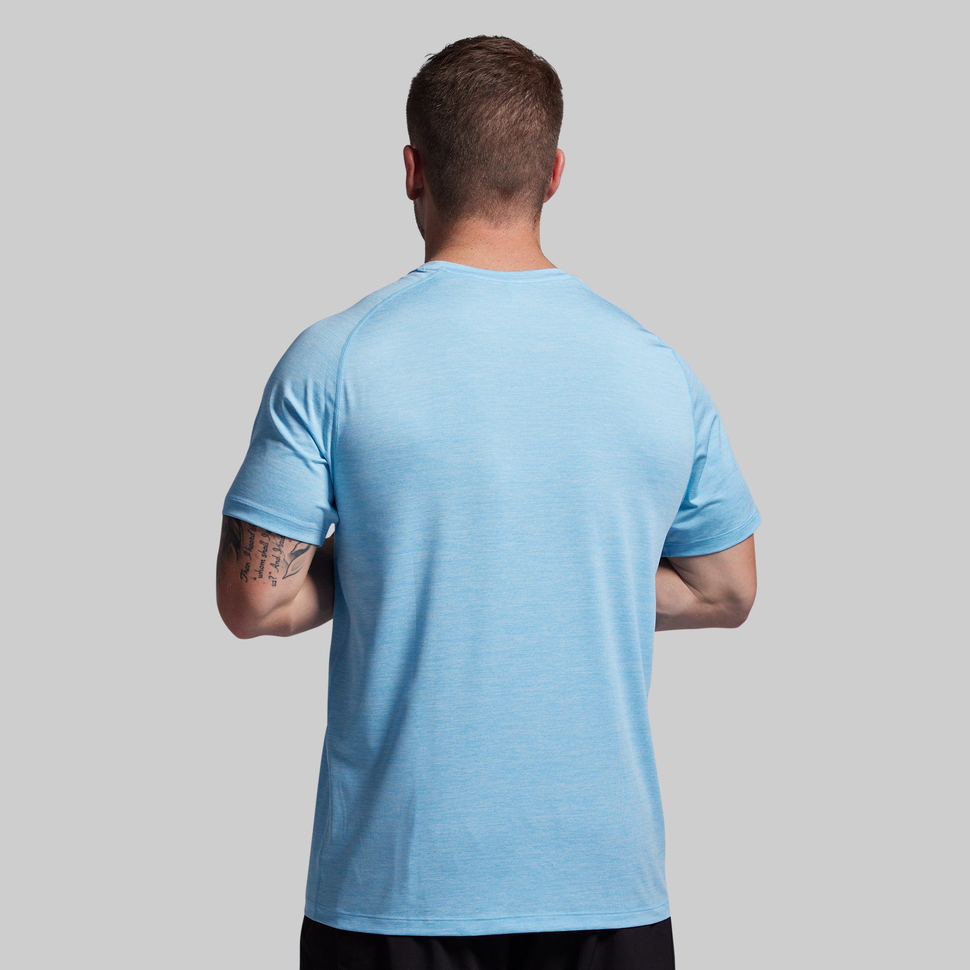 Man wearing a light blue t-shirt on a gray background