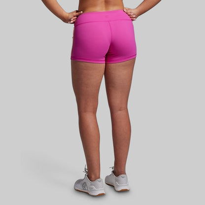 Person wearing bright pink athletic shorts on a gray background