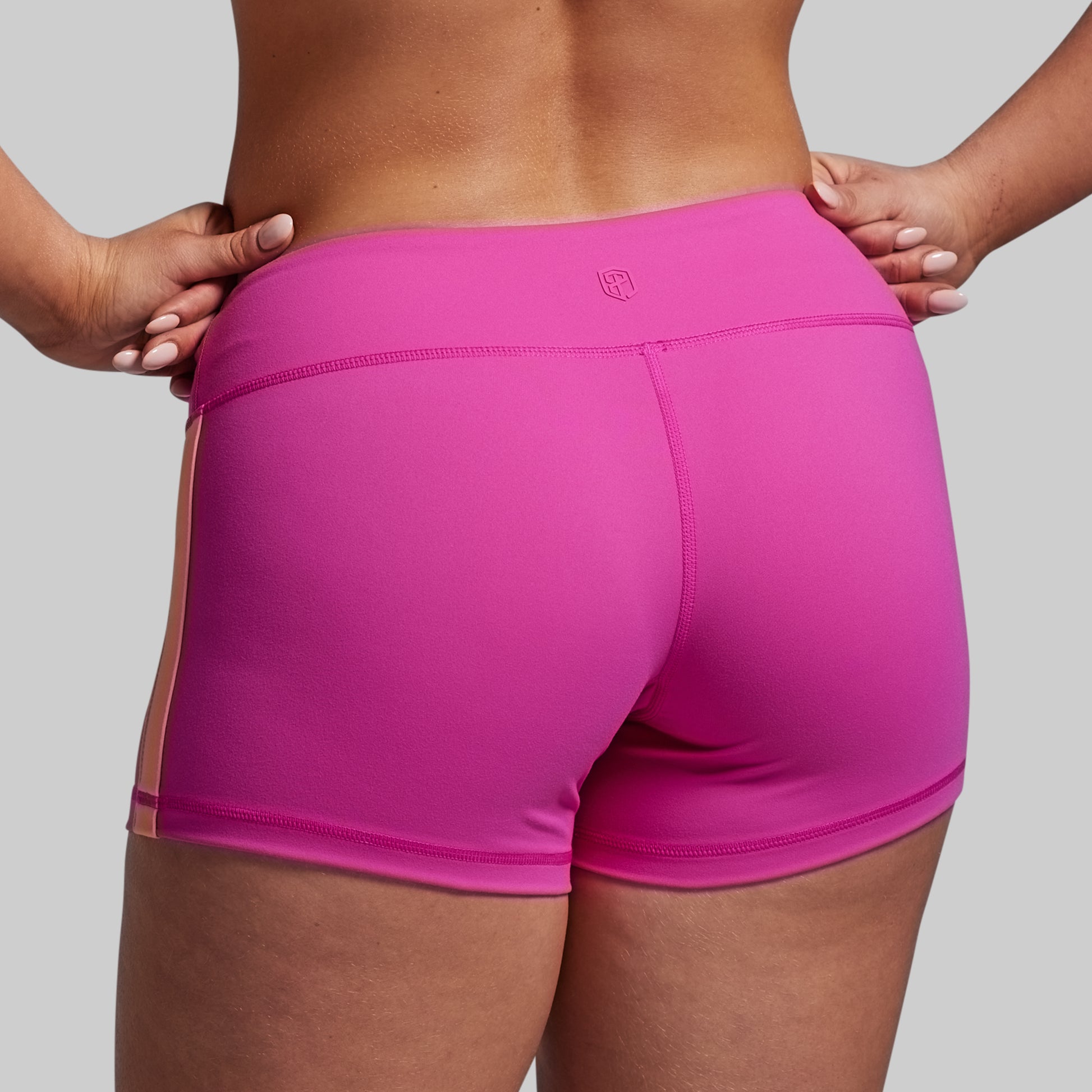 Person wearing bright pink athletic shorts on a plain background
