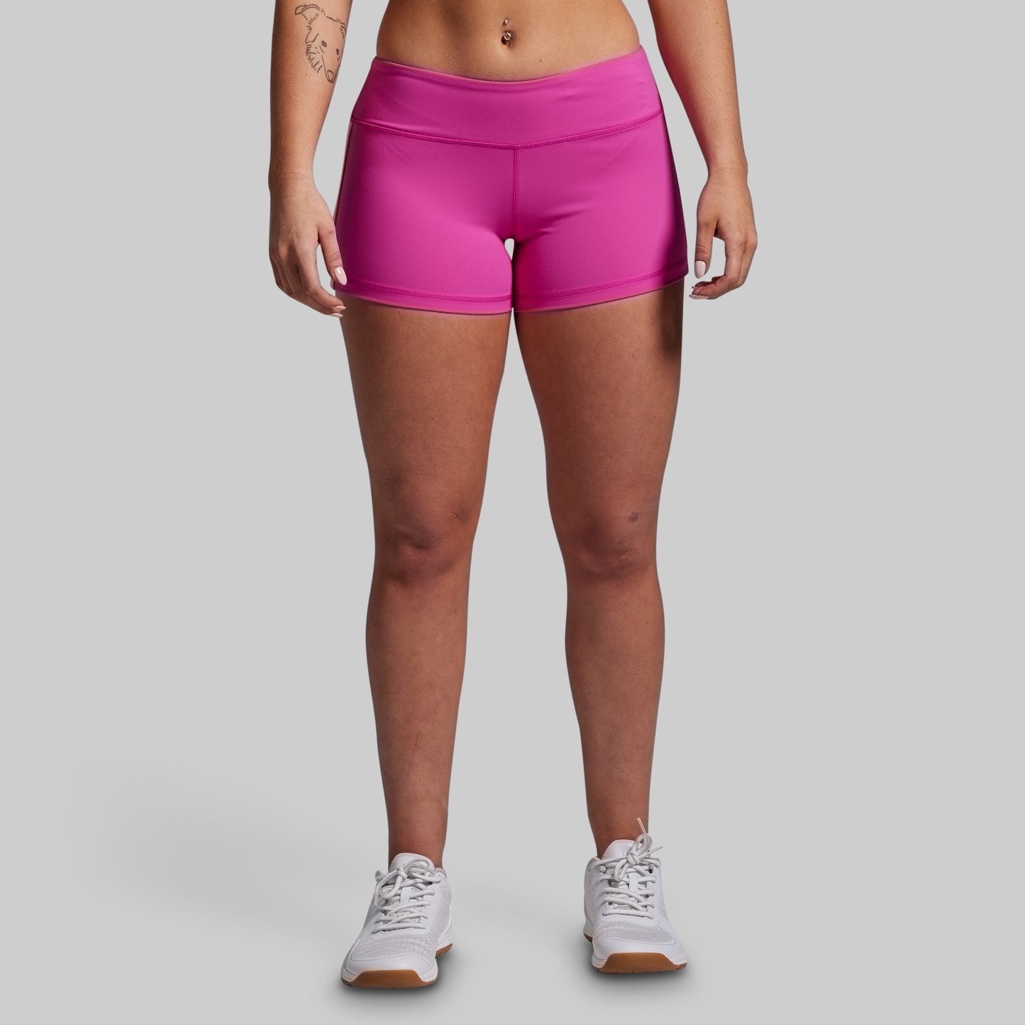 Person wearing bright pink athletic shorts on a gray background