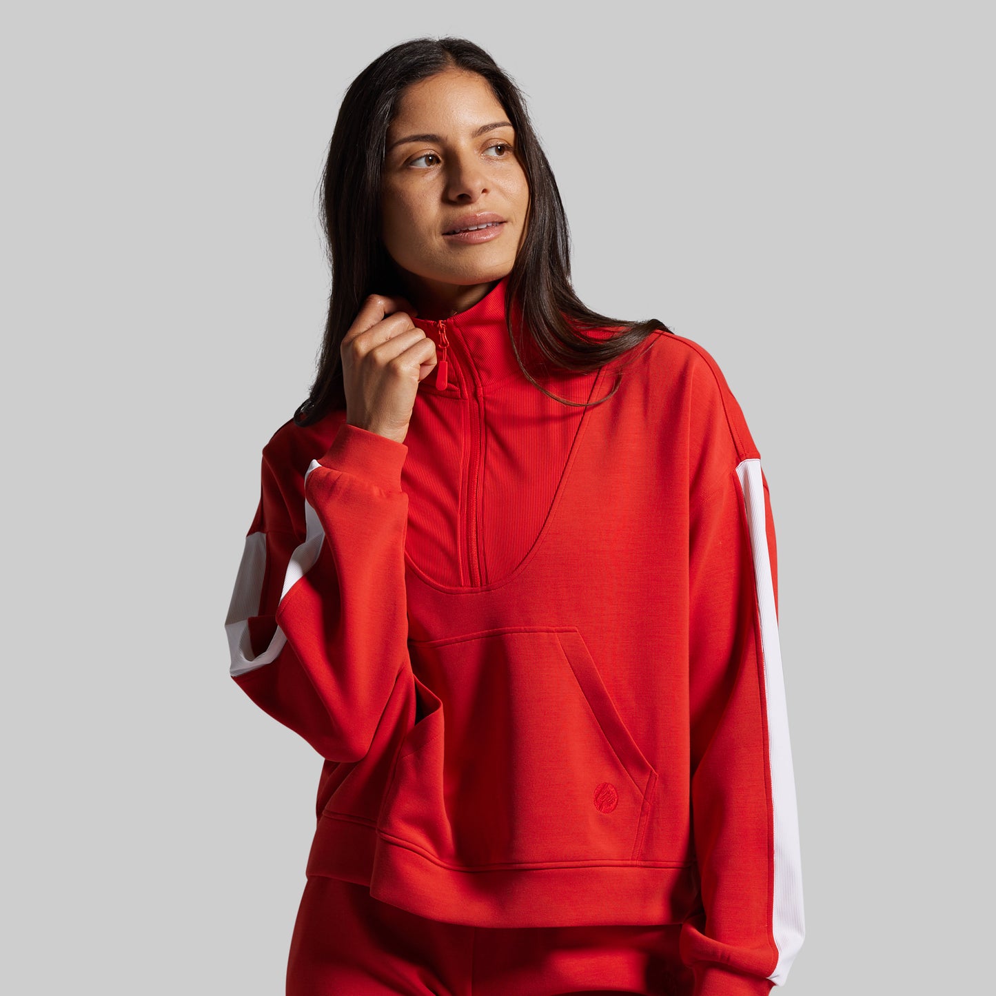 Person wearing a red pullover with white accents on a gray background