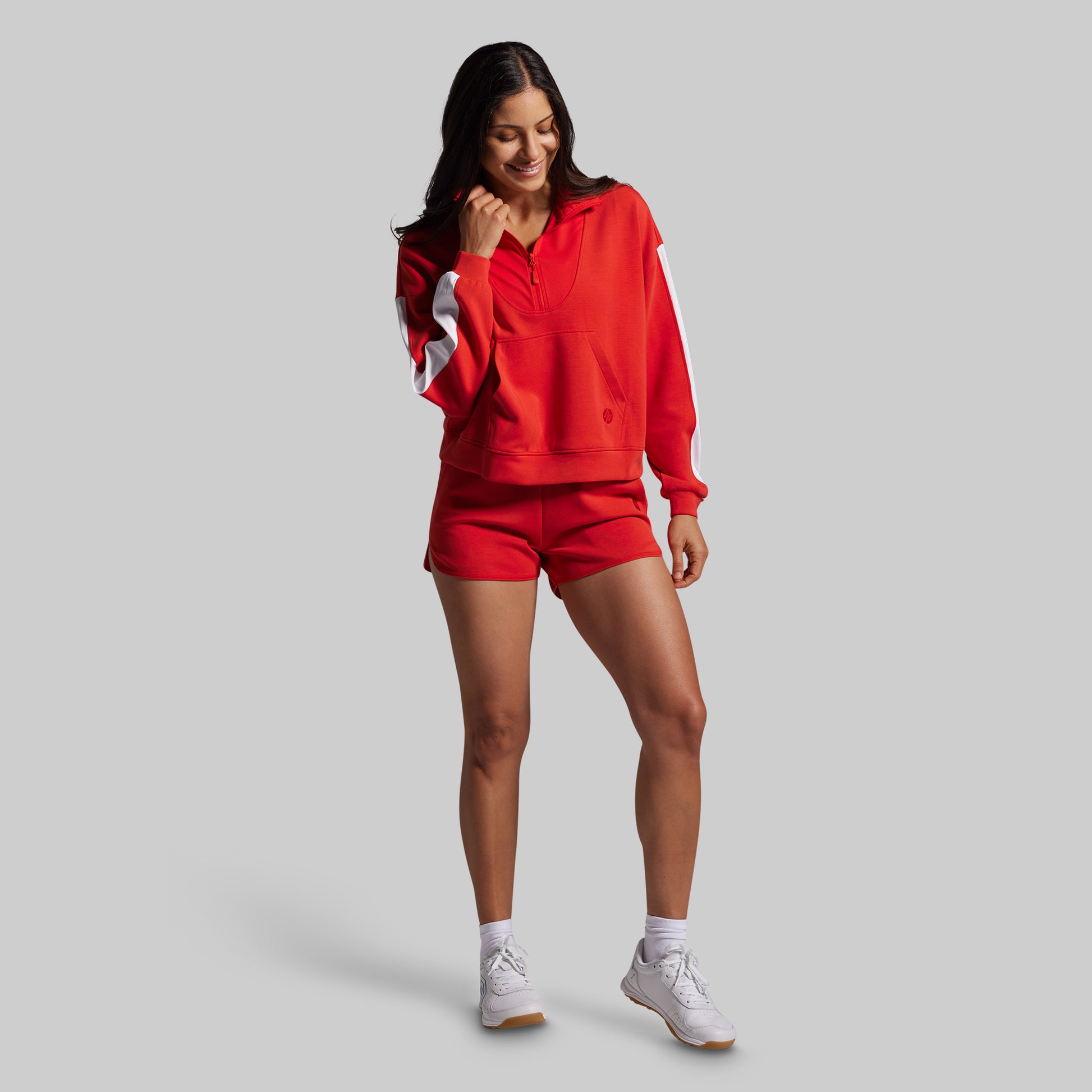 Woman wearing a red sweatshirt and shorts on a gray background