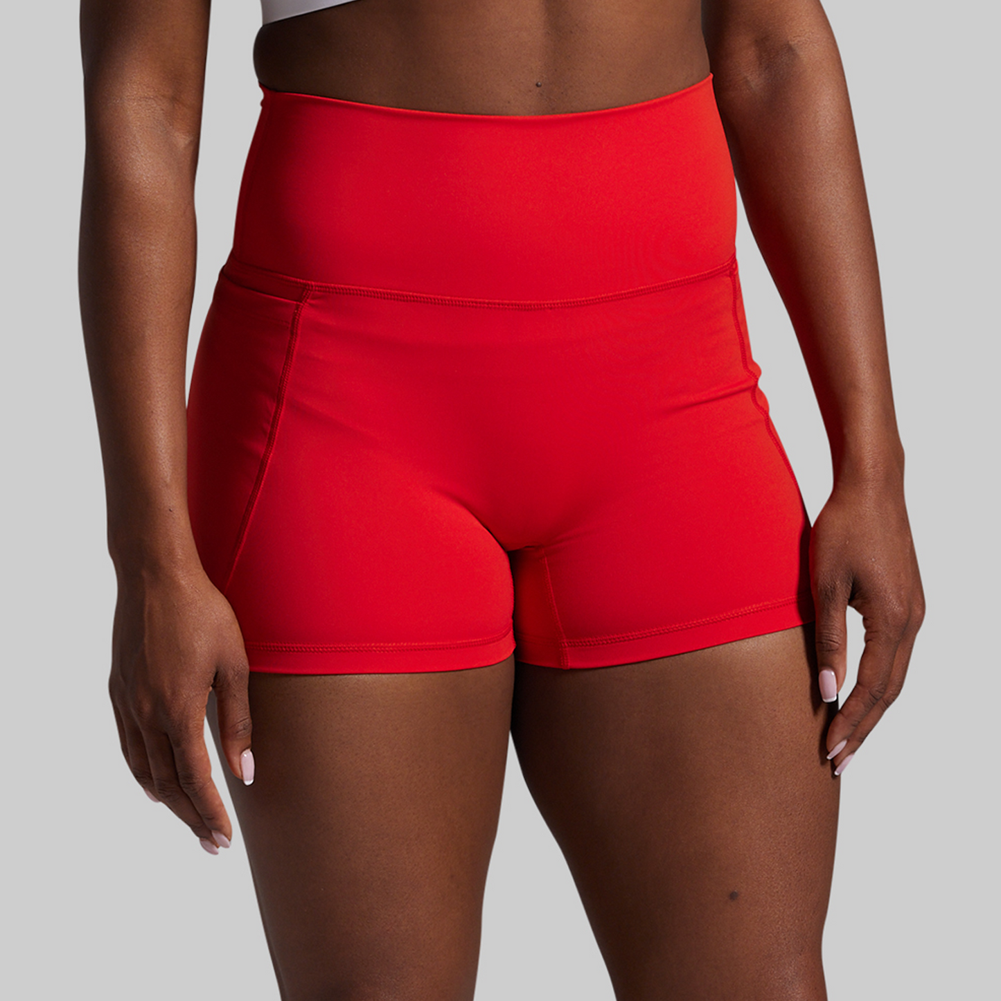 Red high-waisted shorts worn by a person on a gray background