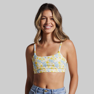 Woman wearing a floral sports bra and jeans on a plain background