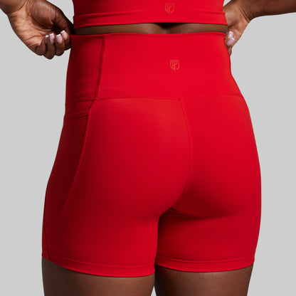 Red athletic shorts with a logo on a gray background