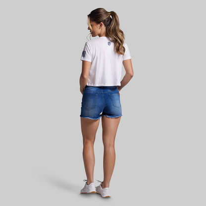 Woman wearing a white t-shirt and blue denim shorts on a gray background