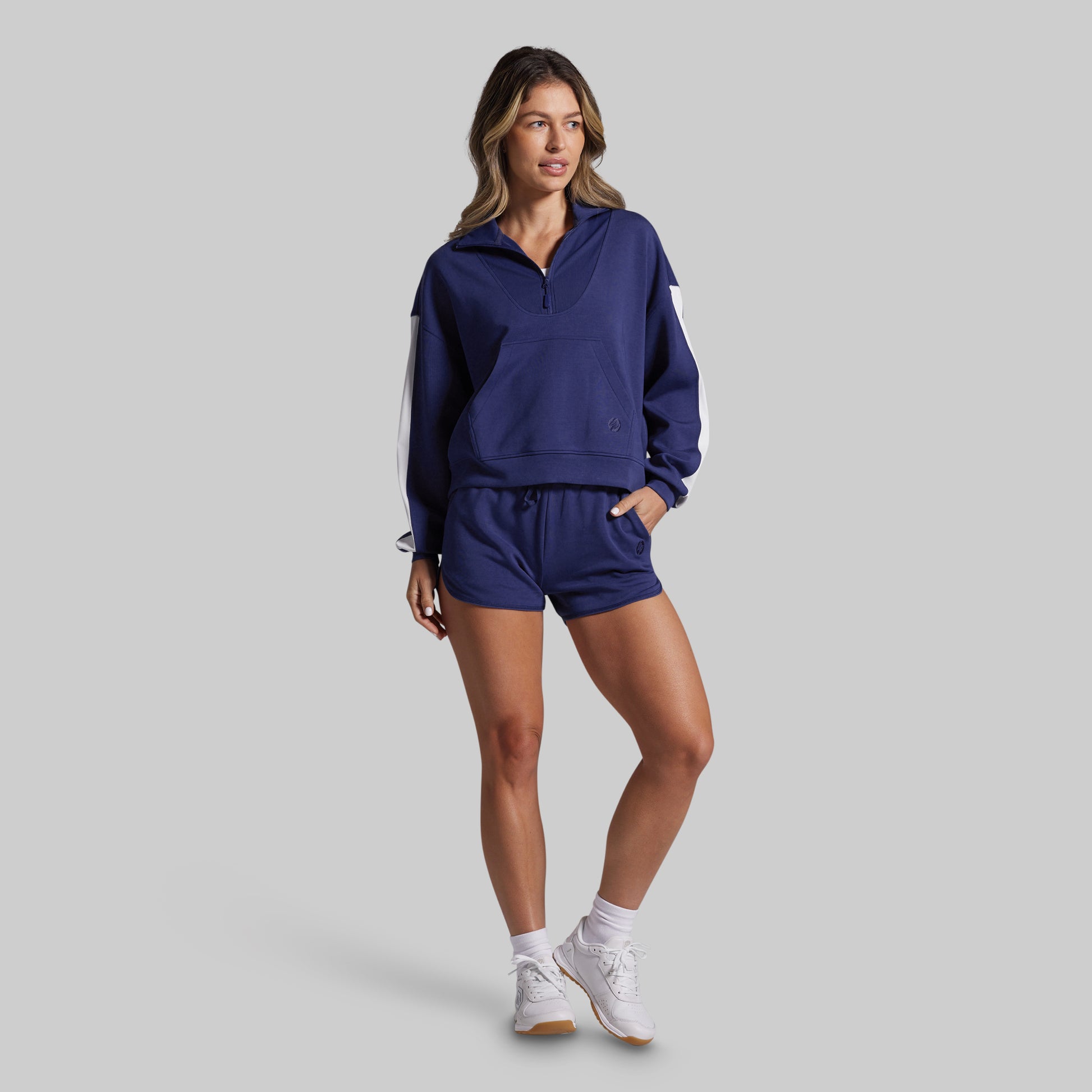 Woman wearing a navy tracksuit on a gray background