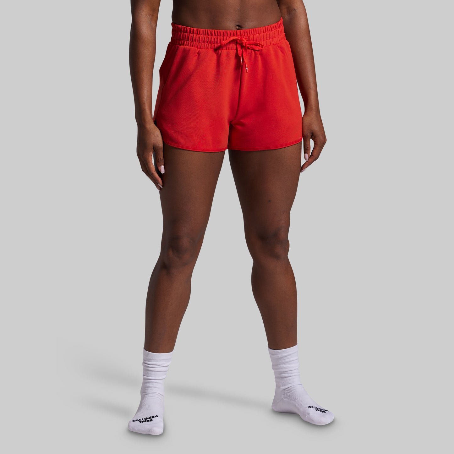 Person wearing red shorts and white socks on a gray background