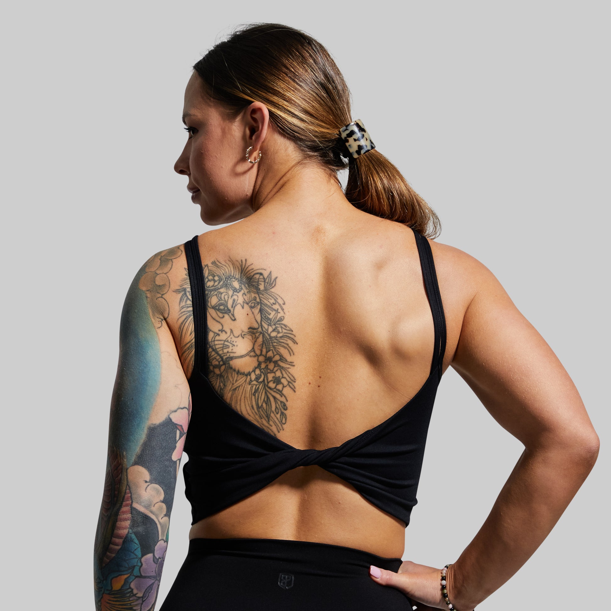 Person wearing a black sports bra with a gray background