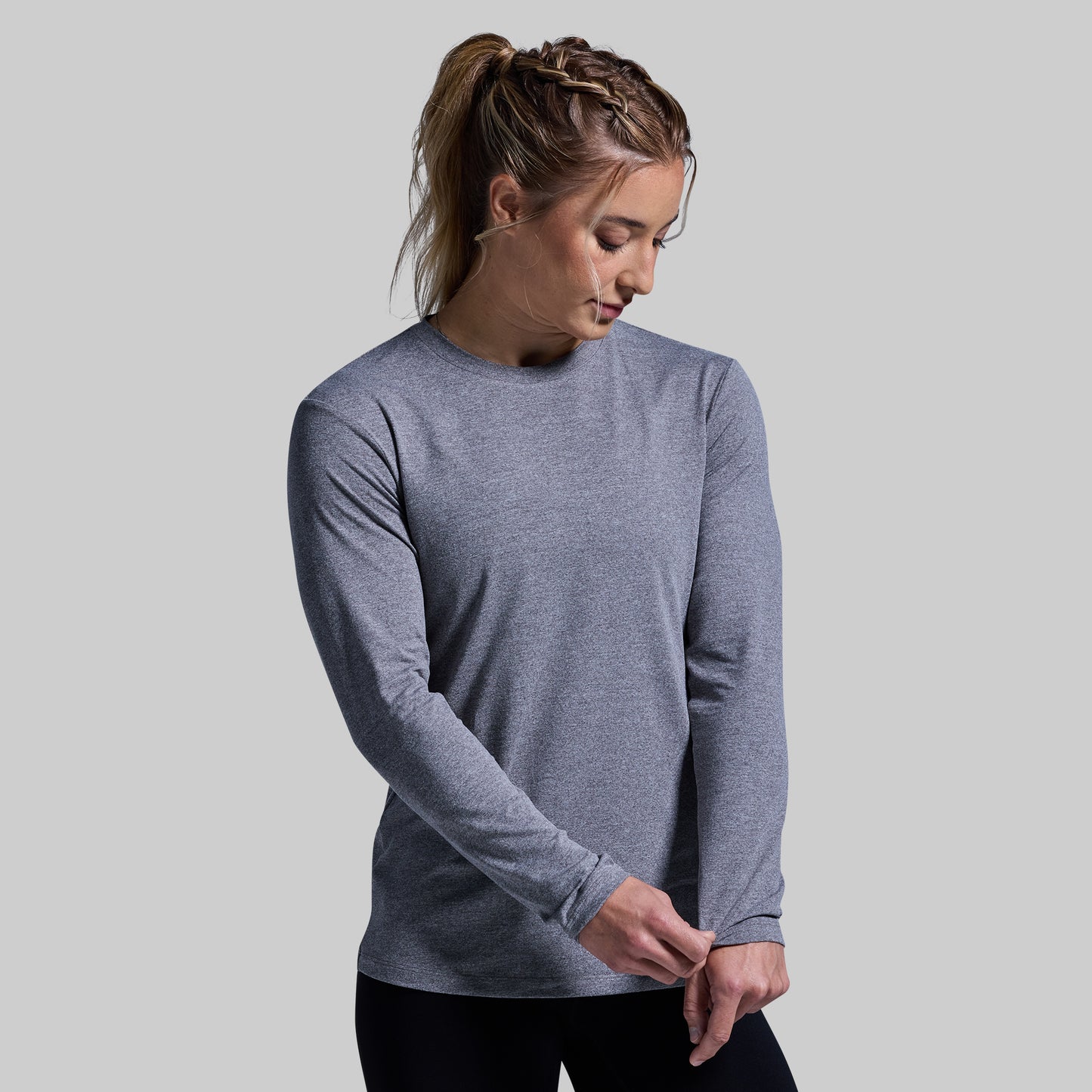 Woman wearing a gray long-sleeve shirt against a plain background