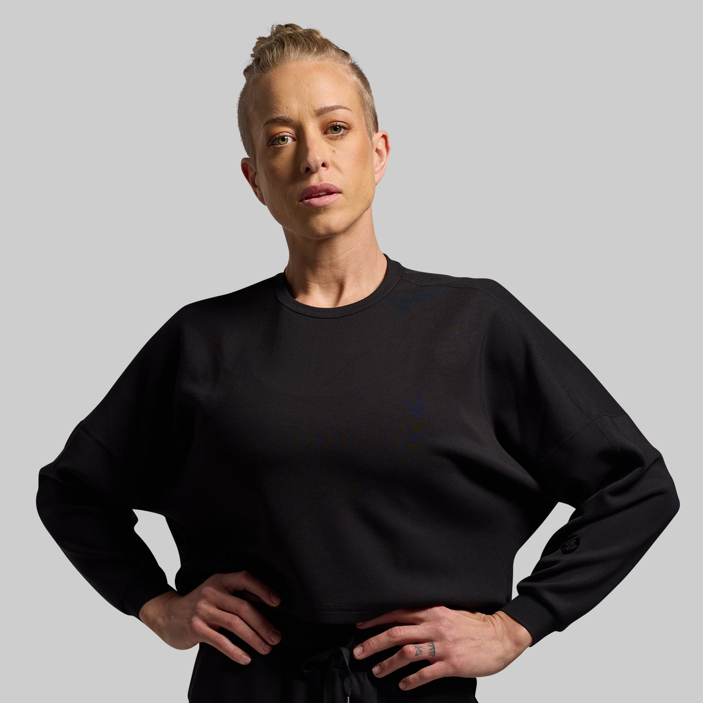 Person wearing a black sweatshirt against a gray background