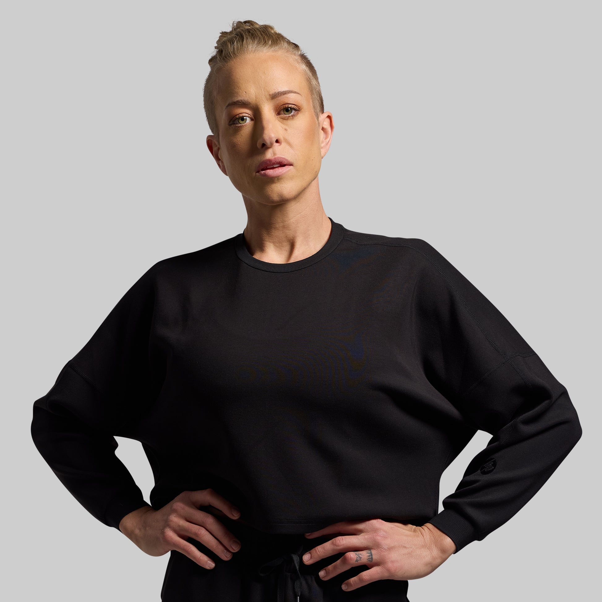 Person wearing a black sweatshirt against a gray background
