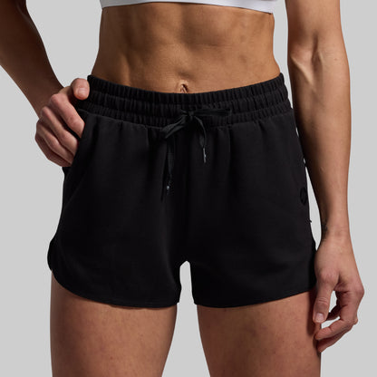Person wearing black shorts on a plain background