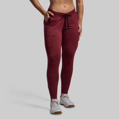 Maroon jogger pants worn by a person on a gray background