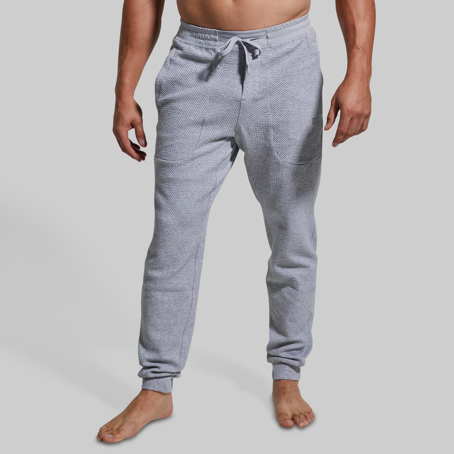 Person wearing gray textured jogger pants on a plain background