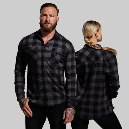 Man and woman wearing black plaid shirts against a gray background