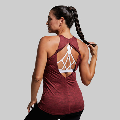 Woman wearing a maroon athletic top with a unique back design on a gray background