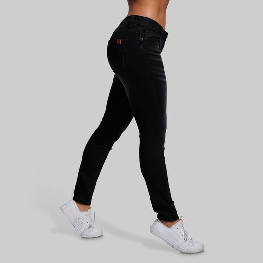 Person wearing black jeans and white sneakers on a gray background