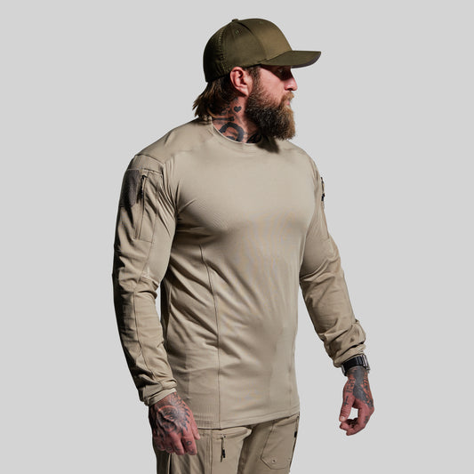 Man wearing a beige long-sleeve shirt and cap on a gray background