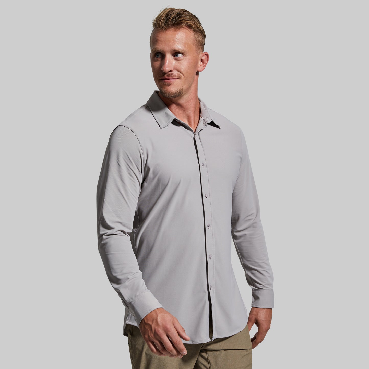 Man wearing a light gray button-up shirt with a plain background