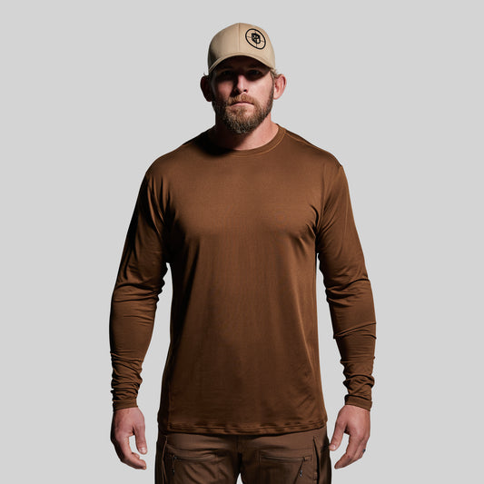 Man wearing a brown long-sleeve shirt and cap on a gray background