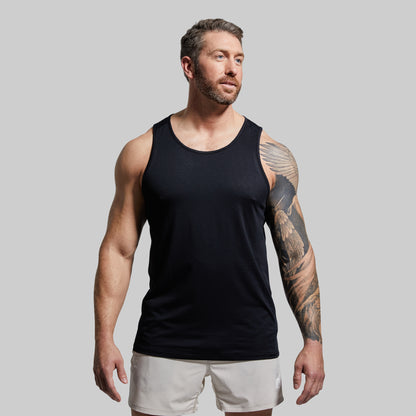 Man wearing a black tank top and white shorts against a gray background