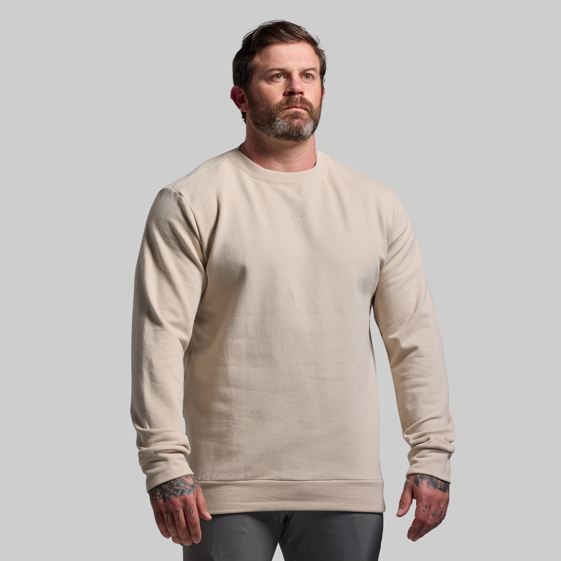 Man wearing a beige sweatshirt against a plain background