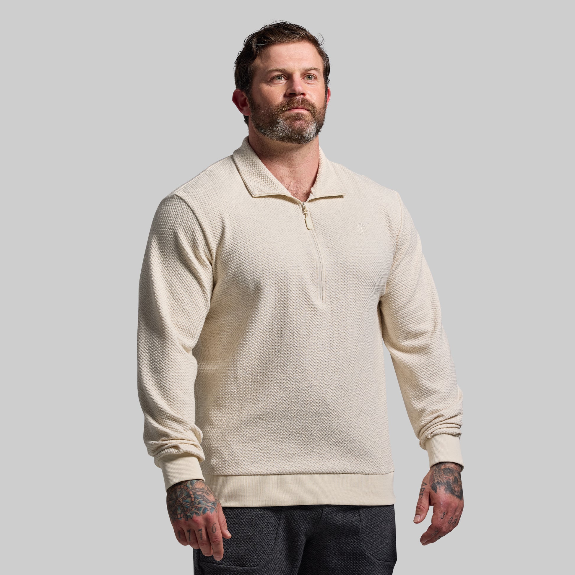 Man wearing a beige textured sweater against a plain background