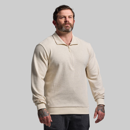 Man wearing a beige textured sweater against a plain background