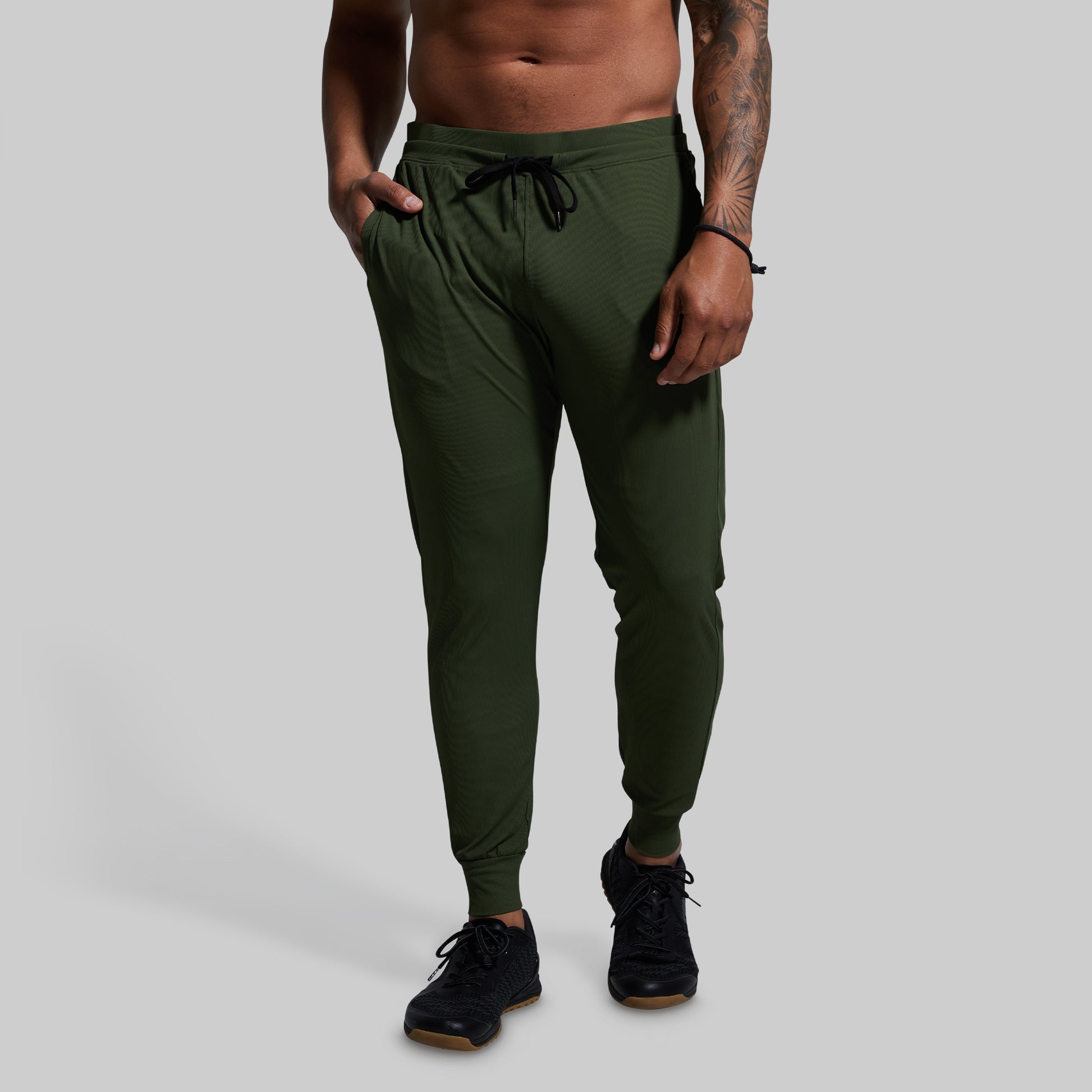 Person wearing green jogger pants on a plain background