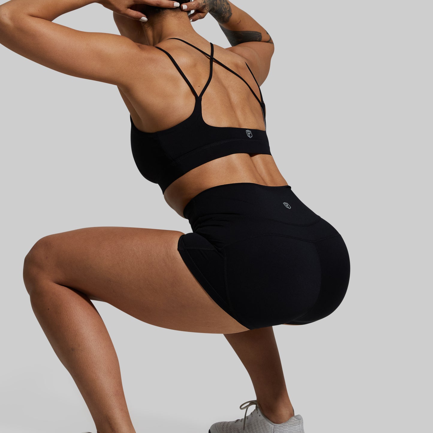 Person wearing a black sports bra and shorts on a gray background