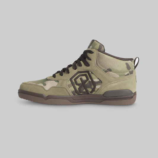 A mid-top sneaker in a green and beige camouflage pattern with dark brown accents, including the sole, laces, and logo, shown from a side profile on a solid gray background.