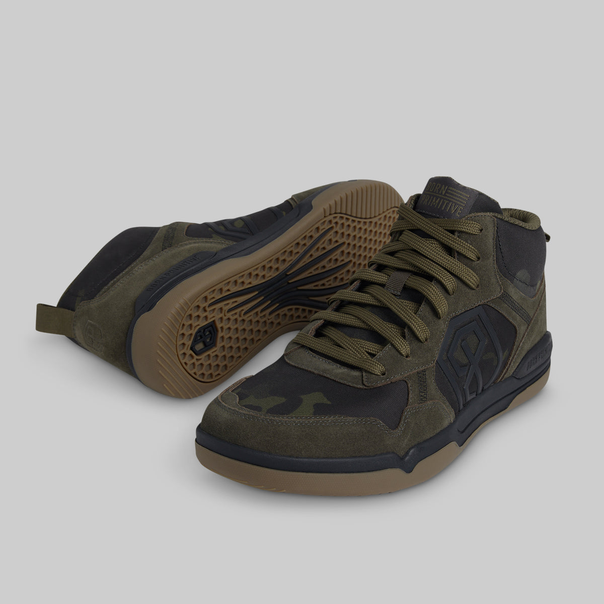 A pair of mid-top athletic sneakers in olive green and black, with a gum-colored sole, shown on a solid gray background.