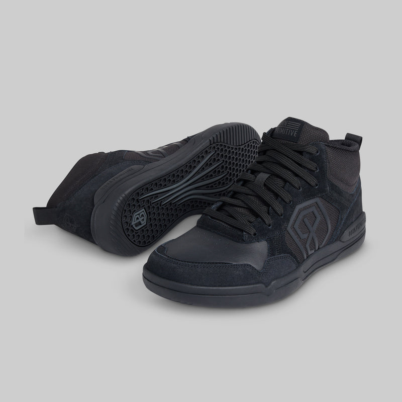 A pair of black mid-top athletic sneakers shown on a plain light gray background, with one shoe standing upright and the other lying on its side to display the sole.