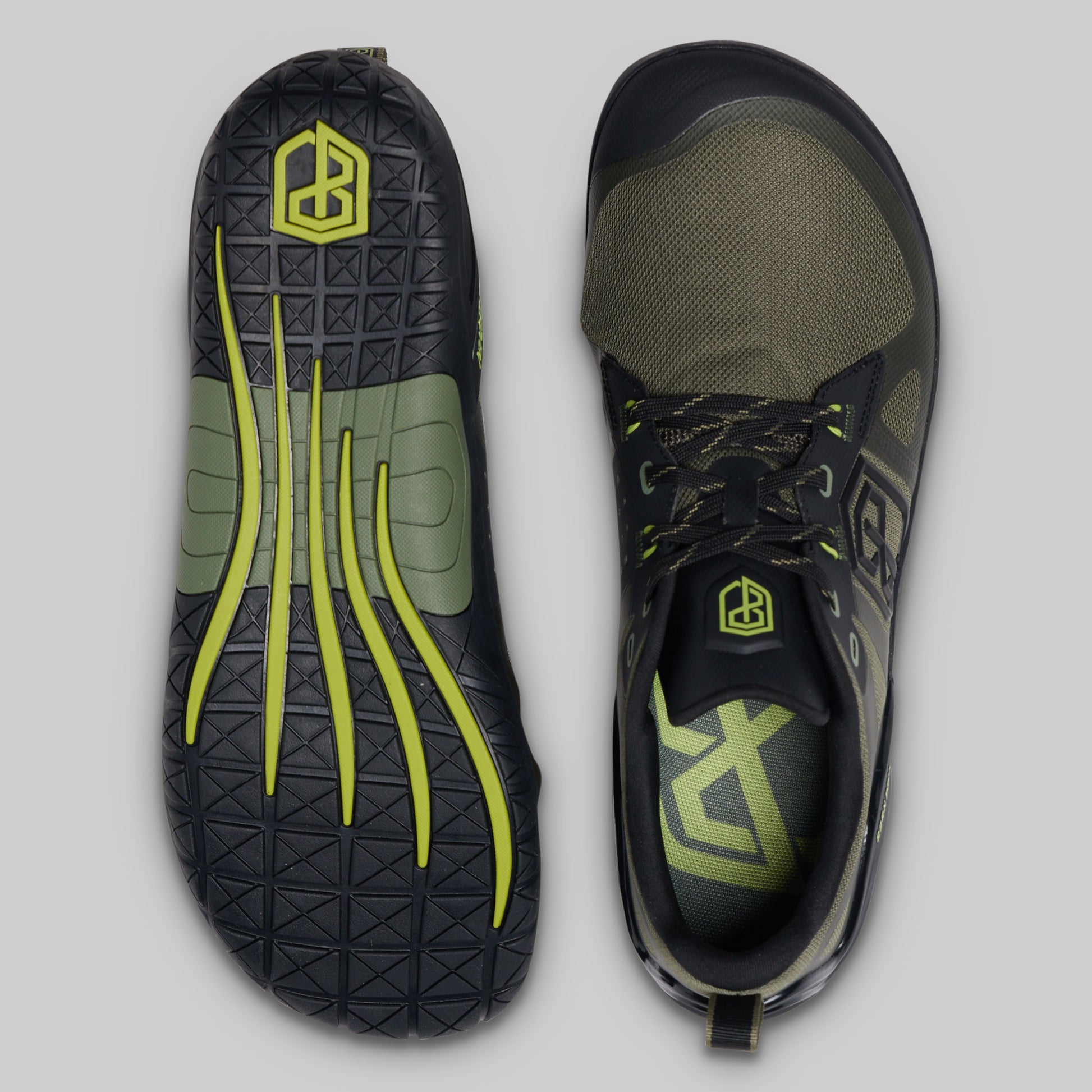 A pair of minimalist training shoes shown from the top and bottom against a neutral gray background. The shoes are primarily black and olive green with bright neon yellow accents, including the logo on the heel and the laces.