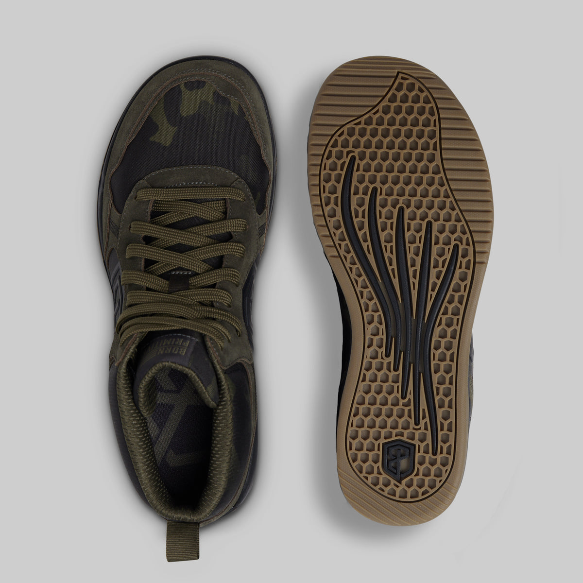 A pair of tactical-style sneakers shown from top and bottom views on a light gray background. The upper is dark olive green with a subtle camouflage pattern, and the outsole is a brown gum rubber with black tread details.