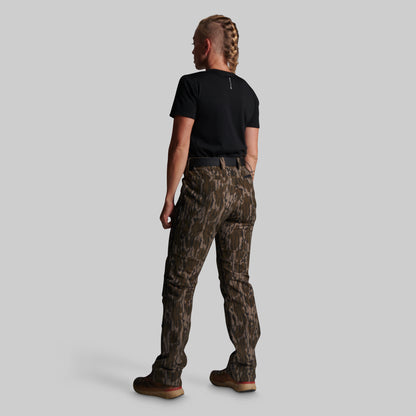 A model shown from the back wearing camouflage cargo pants, a black t-shirt, and brown boots against a solid gray background.